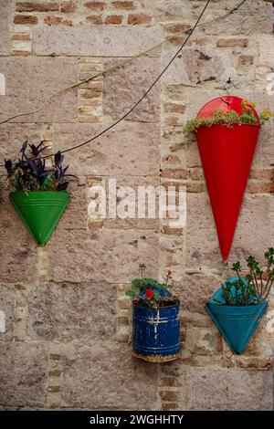 Various color flower pots hanging on a wall. Stock Photo
