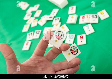 Male hand holding two joker plastic tiles from the game rummikub, rummicub or  okey in Turkey o green background Stock Photo