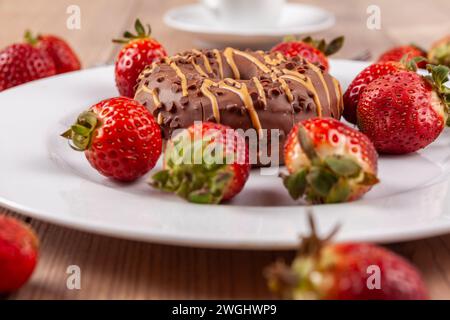 A Delicious Chocolate Doughnut On A White Plate, Garnished With A Fresh Strawberry, On A Rustic Wooden Base. Stock Photo
