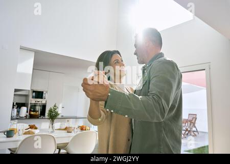 Happy affectionate romantic middle aged mature couple dancing at home Stock Photo