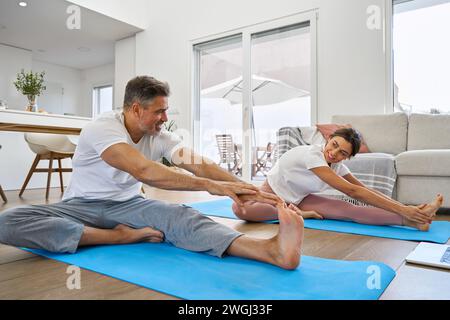 Fit sporty happy middle aged family couple stretching together at home. Stock Photo