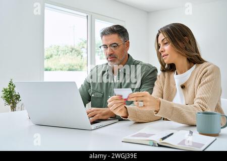 Middle aged couple using laptop computer holding credit card doing shopping. Stock Photo