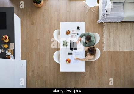 Mature couple using laptop computer sitting at table in living room. Top view. Stock Photo