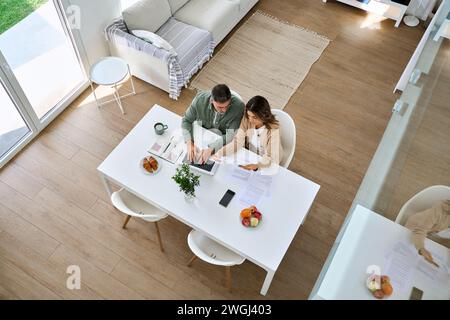 Mature couple using laptop paying bills sitting at home living room. Top view. Stock Photo