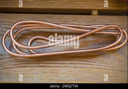 copper wire on wooden background, selective focus Large of orange copper wire  Stock Photo