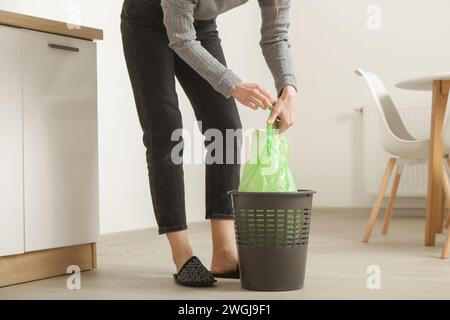 Housewife throwing away garbage, taking of plastic garbage bag from the trash bin in the apartment Stock Photo