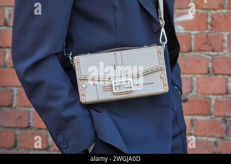 MILAN, ITALY - JANUARY 13, 2024: Man with beige Fendi bag and blue jacket and trousers before Fendi fashion show, Milan Fashion Week street style Stock Photo