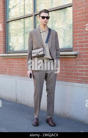 MILAN, ITALY - JANUARY 13, 2024: Man with beige Fendi bag and suit before Fendi fashion show, Milan Fashion Week street style Stock Photo