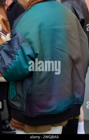 MILAN, ITALY - JANUARY 14, 2024: Man with green, grey and blue bomber jacket before K-Way fashion show, Milan Fashion Week street style Stock Photo