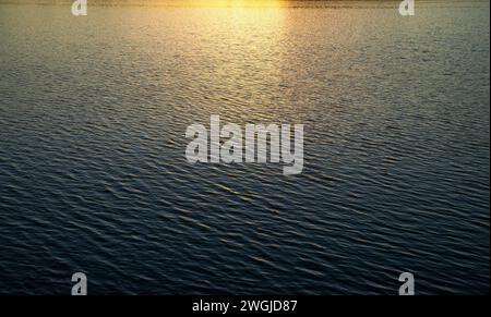 Water surface with waves under the rays of the setting sun. Stock Photo