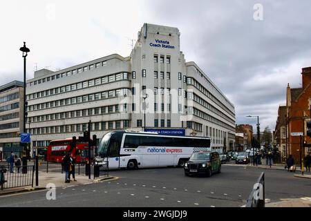 A National Express coach turning in front of Victoria Coach Station with a black taxi and red bus from Elizabeth Bridge London England United Kingdom Stock Photo