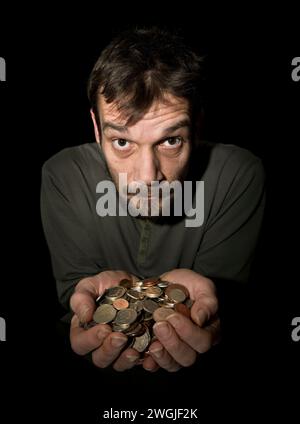 Caucasian Male (42 years old) with hands held out crammed full with loose change in sterling currency, with face looking up as if he cant believe his Stock Photo