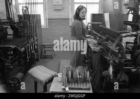 Young woman factory work, working in the textile industry at Salts Mill, West Yorkshire. 1980s UK. She is wearing ear defenders. Working on the factory floor the noise was deafening. England1981 HOMER SYKES Stock Photo