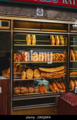 A glass display case showcasing an assortment of fresh bread and rolls in Istanbul, Turkey Stock Photo