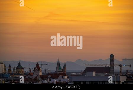 Munich, Germany. 05th Feb, 2024. The backdrop of the Bavarian capital, whose center is marked by the 99-meter-high towers of the Frauenkirche (r), can be seen in the evening against the snow-covered Alpine panorama. The distance between the landmark and the Alps is around 100 kilometers and can only be enjoyed when the foehn wind is blowing. Credit: Peter Kneffel/dpa/Alamy Live News Stock Photo