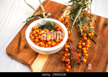 Freshly picked sea buckthorn berries on a branch. Sea buckthorn, harvested in the fall and torn from the branches, poured into a plate, ready for free Stock Photo