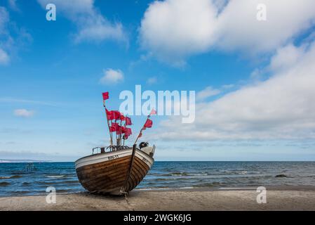 Ein Fischerboot am Strand von Binz auf Rügen mit roten Fahnen der Netzbojen *** A fishing boat on the beach of Binz on Rügen with red flags of the net buoys Stock Photo
