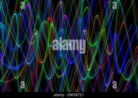 Multi-colored lines in the shape of waves on a black background. Long exposure photography Stock Photo