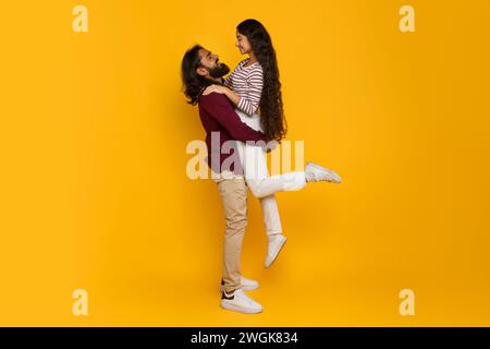 Loving handsome indian guy lifting up his beautiful girlfriend Stock Photo