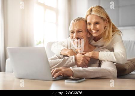 Loving european retired couple planning vacation together, using laptop Stock Photo