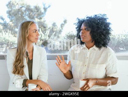 Coworkers chatting and drinking coffee on a break from work. Business concept. Stock Photo