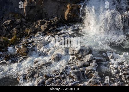 Detail of the bottom of the waterfall. Stones and rock and flowing water, partly frozen into big pieces of ice. Autumn in north-east Iceland, Rjukanda Stock Photo