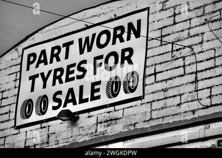 Barry, Vale of Glamorgan, Wales 02 Feb 2024: Tyre sale and fitting advertised in an arched vintage industrial unit on dockland. Dirty white brick wall Stock Photo