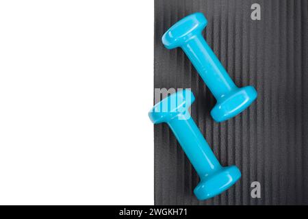 Yoga mat with a set of dumbbells isolated on a white background Stock Photo