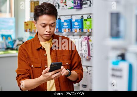 asian electronics ship owner messaging on mobile phone in retail space, small business concept Stock Photo