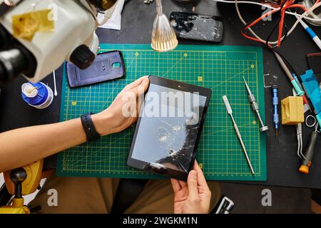 cropped view of skilled technician holding digital tablet with broken touchscreen in repair shop Stock Photo