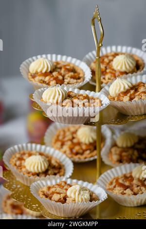 Birthday cupcakes on three tiered display stand close up festive balloons in the background Stock Photo