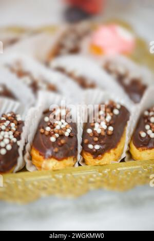 Small eclairs sweets backed pastry with colorful sprinkles close up party food Stock Photo