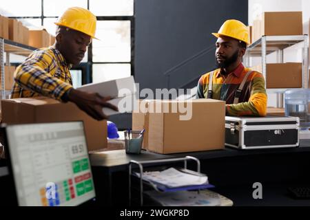 Warehouse employees putting packed boxes on counter desk ready for shipment. African american e commerce retail storehouse managers preparing customer packages for transportation Stock Photo