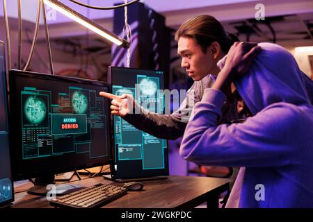 Unhappy hackers failing to crack password while breaking into computer network. Two disappointed criminals getting access denied while hacking website and attempting to pass security system Stock Photo
