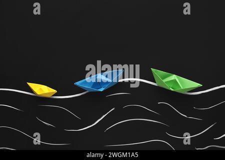 Colorful origami boats and drawn waves on black chalkboard Stock Photo