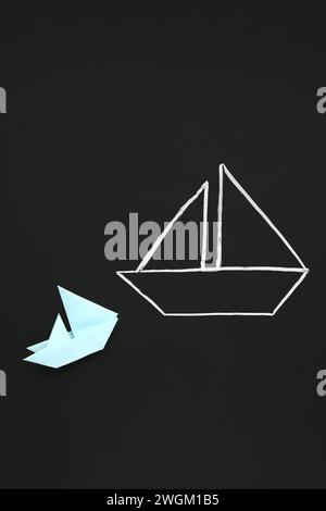 Drawn and colorful paper boats on black chalkboard Stock Photo