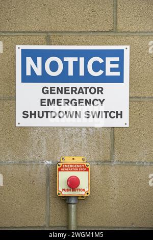 generator emergency shutdown switch and signs on block wall Stock Photo