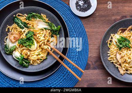 Servings of chow mein noodles with vegetables and spicy pork, ready for eating. Stock Photo