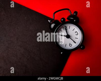 Top view black alarm clock on a red and black background with copy space Stock Photo