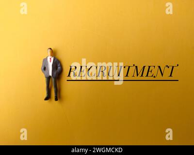 Top view miniature people with text RECRUITMENT on yellow background. Stock Photo