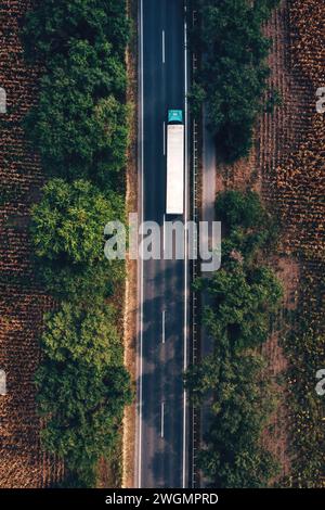 Trucking and freight transport logistic concept, aerial shot of semi-truck on highway from drone pov, directly above Stock Photo