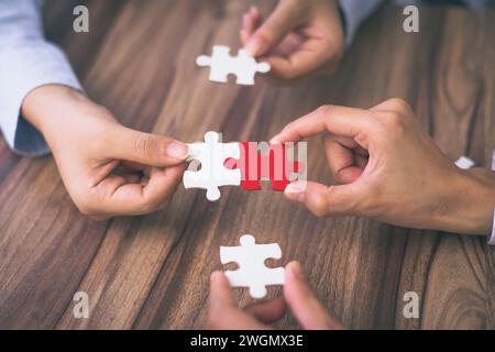 Hand put the last piece of jigsaw puzzle to complete the mission. Concept of connecting jigsaw pieces, problem solving, teamwork and success. Stock Photo