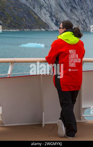 World Leader in Exploration Travel on back of Hurtigruten red jacket clothing on cruise ship at Greenland in July Stock Photo