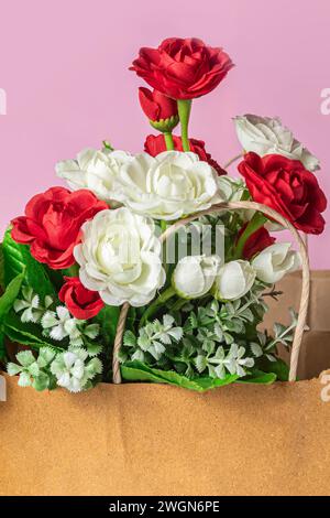 Bouquet of red and white roses in paper bag on pink background Stock Photo