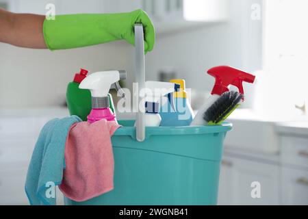 Woman holding bucket with cleaning supplies in kitchen, closeup Stock Photo