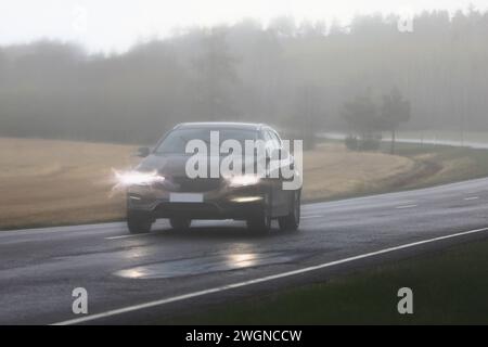 Car driving along highway on a rainy, stormy day with low visibility, bright headlights distorted in-camera. Stock Photo