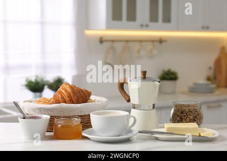 Breakfast served in kitchen. Fresh coffee, granola, croissants, jam, butter and honey on white table Stock Photo