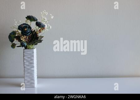 Home decoration in the form of a vase with artificial flowers. Bouquet of blue roses and a branch of white flowers look aesthetically pleasing Stock Photo