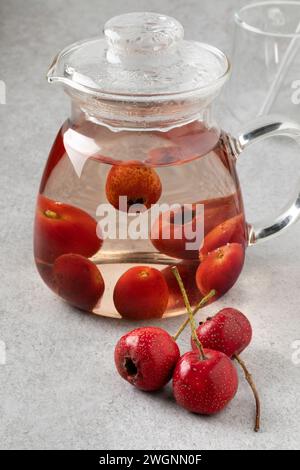 Glass teapot with red hawthorne berry tea close up and fresh hawthorne berries Stock Photo