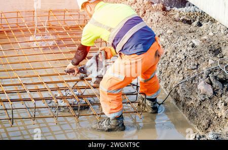 Builder using electric braker fot breaking concrete from the top of pile to fit reinforcement cage on top of it Stock Photo